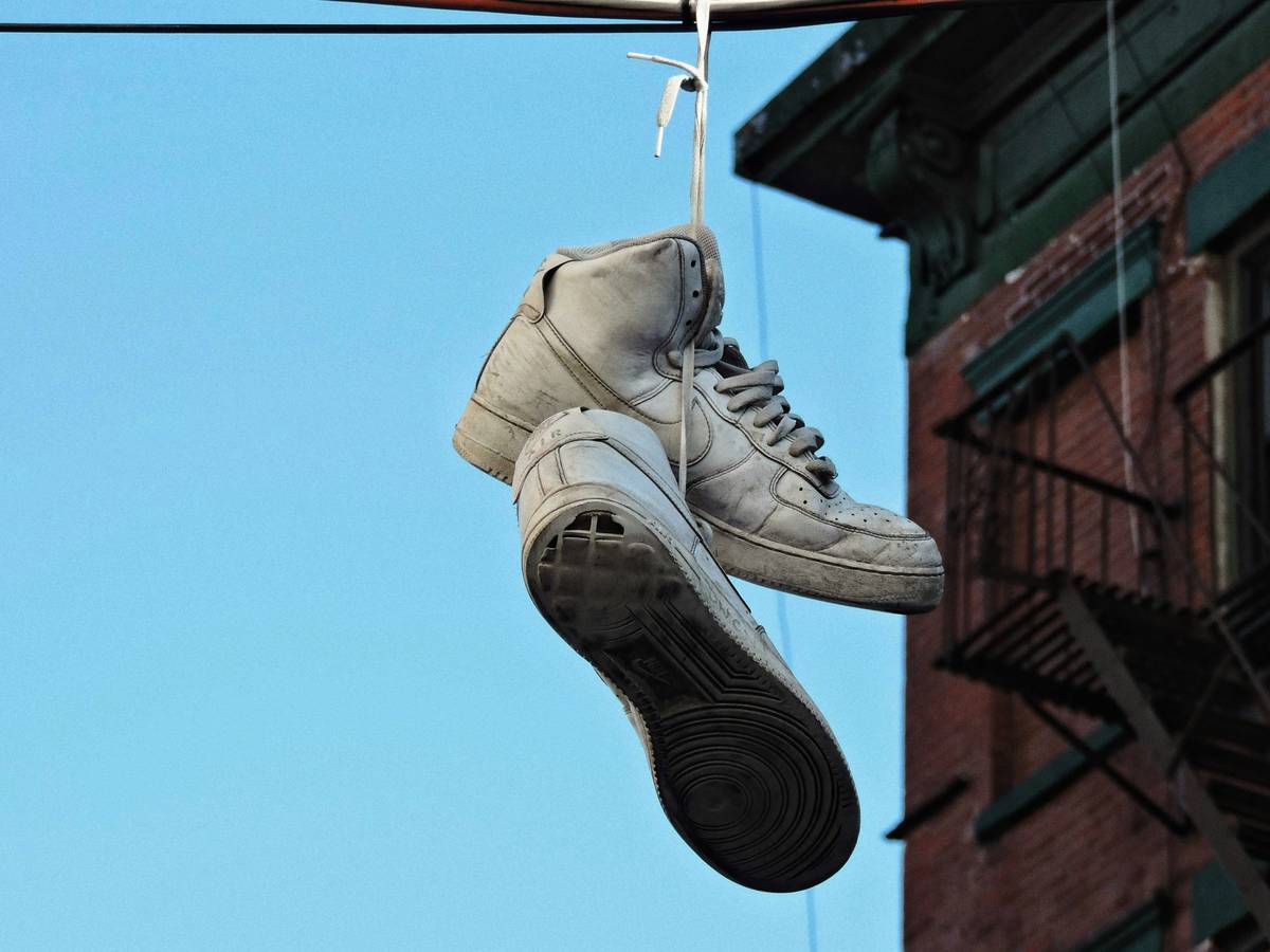 Close-up of hands using sneaker cleaning kits on white athletic shoes with foam applicator